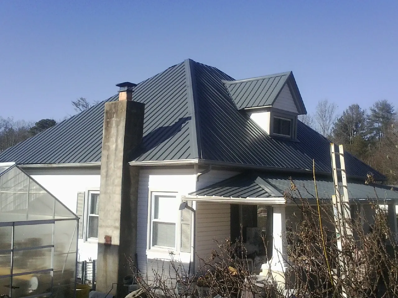 Dark blue standing seam metal roof on a white farmhouse with dormer — Slate & Tile Roof Repair by Roofing Brothers in Andale