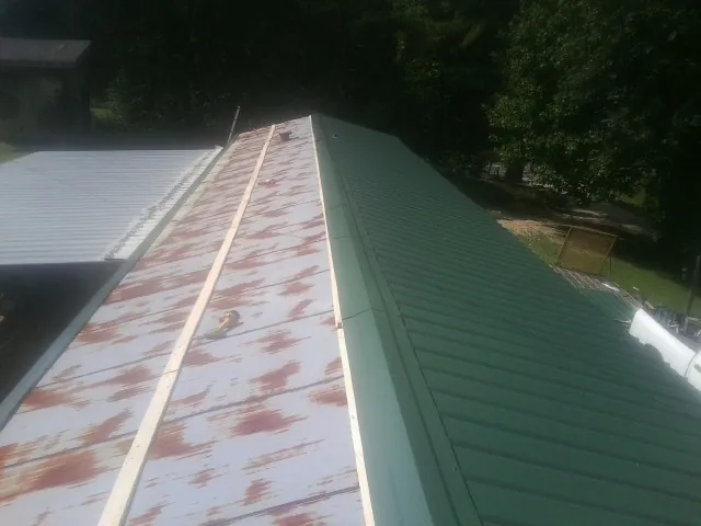 Old rusted panels beside newly installed green metal roofing — Wind Damage Roof Repair by Roofing Brothers in Andale