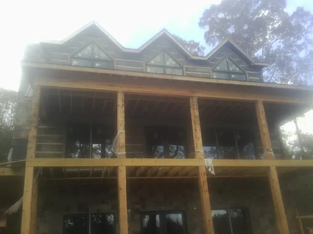 Dormers and porch framing on a large log home under construction — Roof Coating work by our crew in Andale