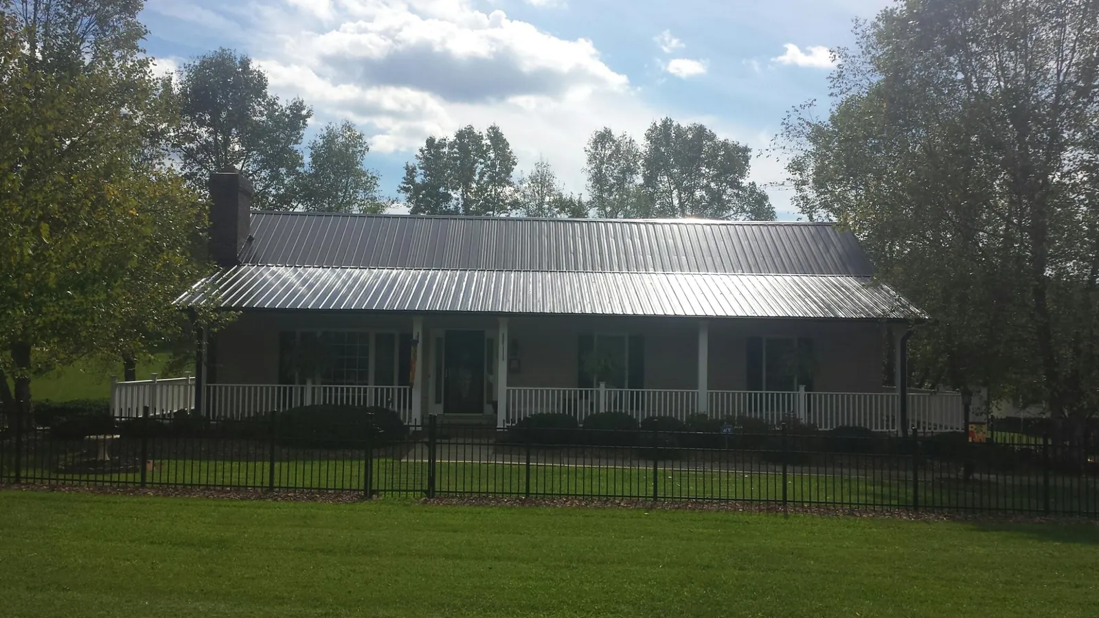 Gray metal roof on a brick ranch with a full width front porch — Gutter Guard Installation work by our crew in Andale