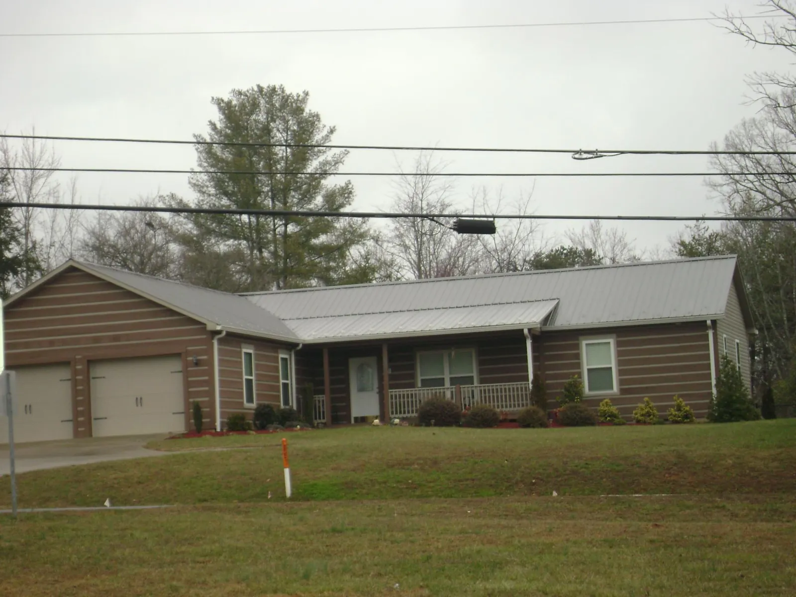 Gray metal roof on a log sided ranch home with a front porch in Andale