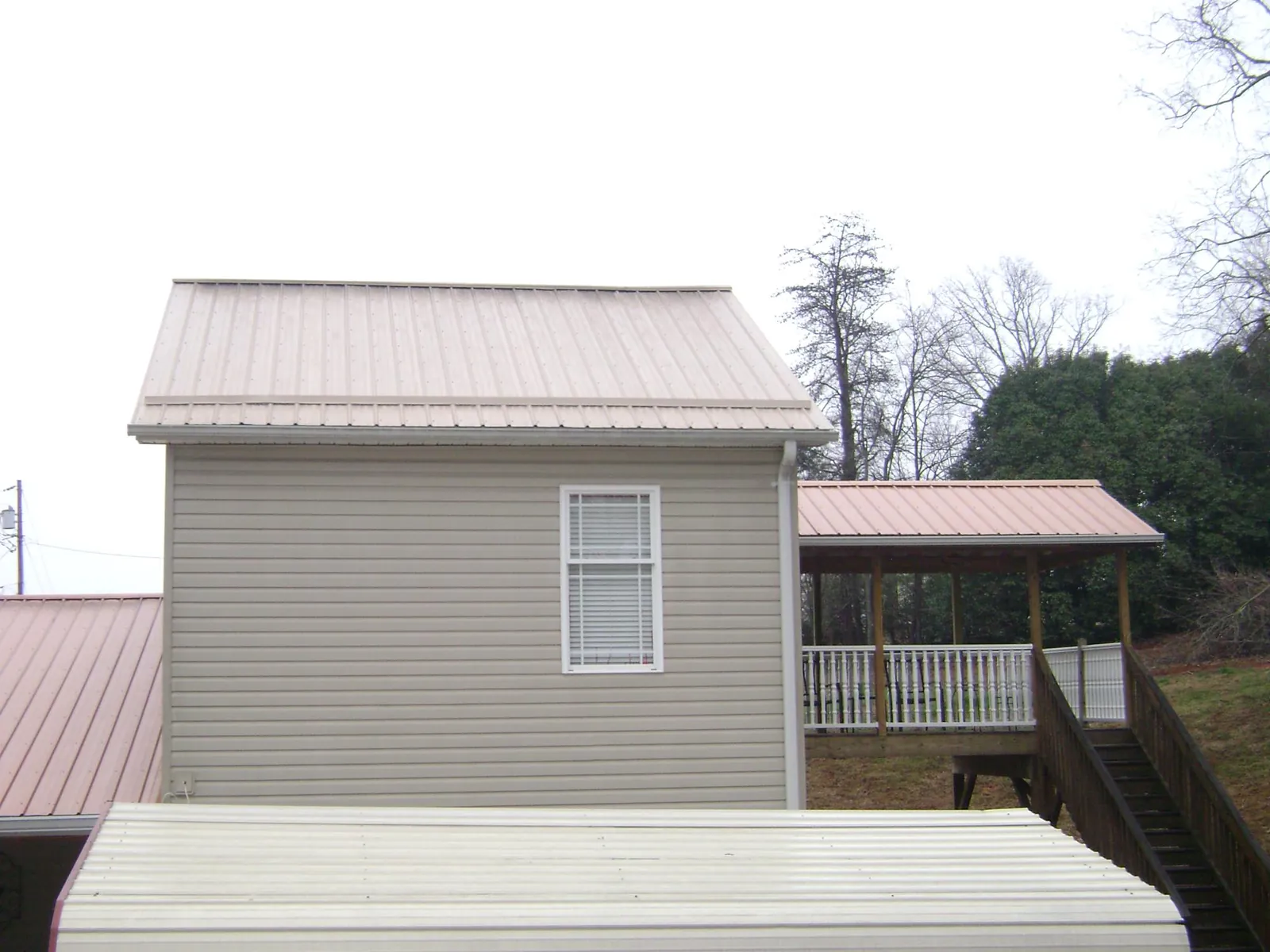 Tan metal roofs on a two story addition and attached porch, from a Roof Replacement job in Andale